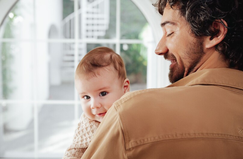 Baby peering over fathers shoulder
