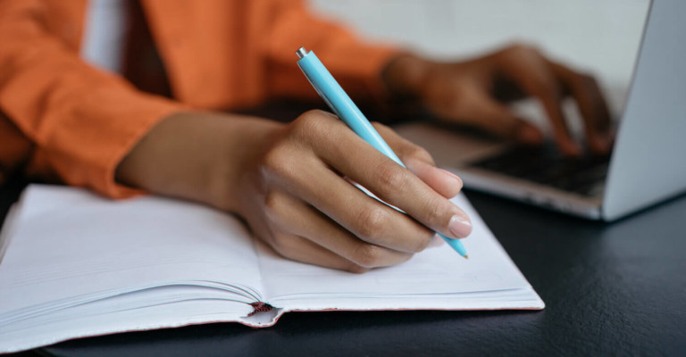 Lady with a notebook and a laptop taking notes