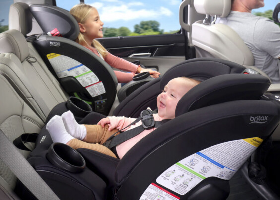 A baby riding rear-facing in an all-in-one car seat and an older child forward-facing in booster mode.