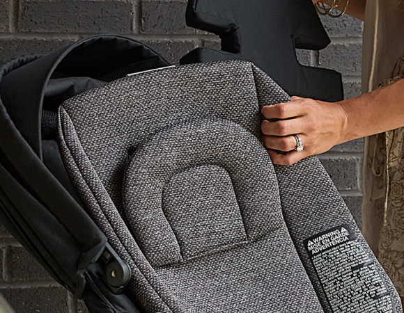 Placing seat inserts and padding into a baby stroller.