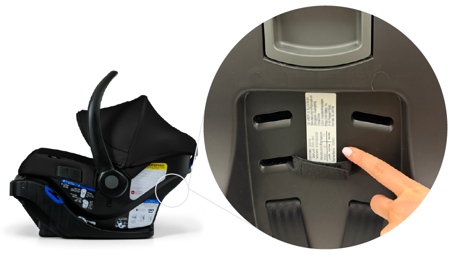 Hand pointing to a label located underneath the infant car seat.