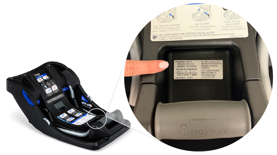 Hand pointing towards a label located under a handle on a car seat base.