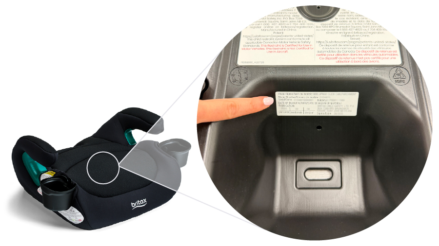 Person pointing to a white label on the underside of a booster car seat.