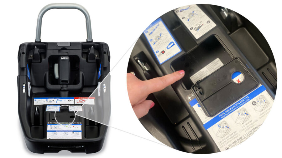 Hand pointing towards a label located inside an opened storage compartment on the infant car seat base
