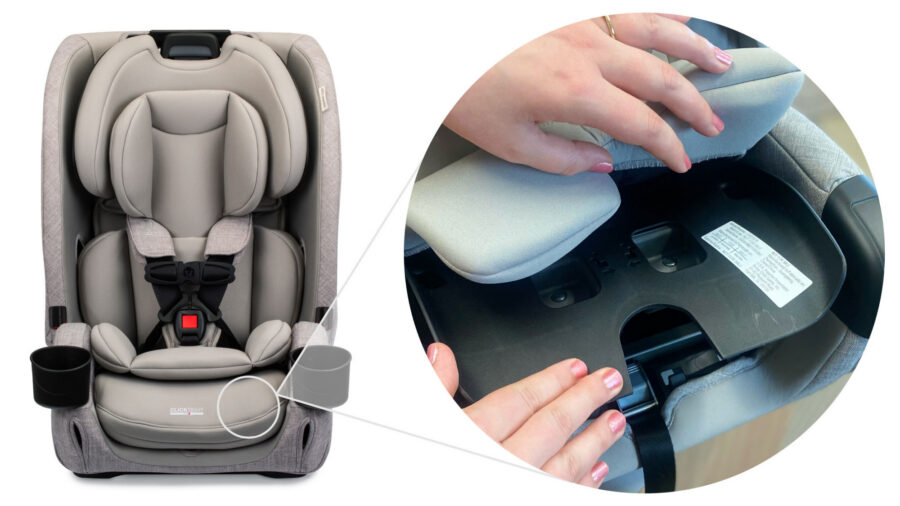 Person lifting up the car seat cover on top of the clicktight compartment to reveal the serial label underneath.