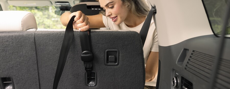 Tightening a car seat tether strap.