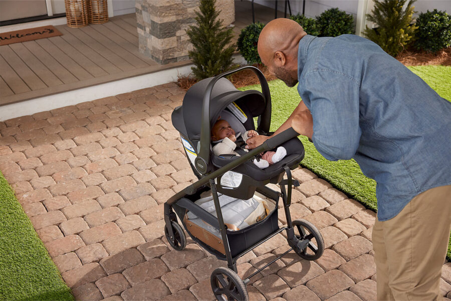 A man interacting with a baby in a travel system stroller.