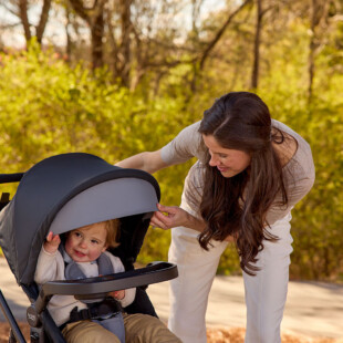 A woman looking down at a toddler in a stroller.