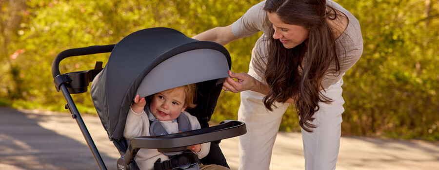 A woman looking down at a toddler in a stroller.