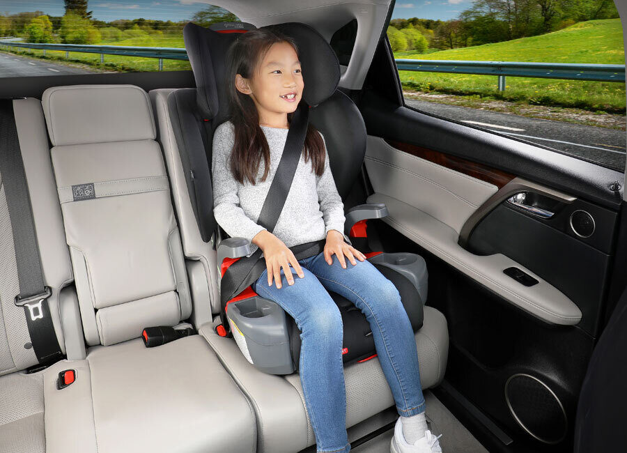 A child in a high-back booster seat in the back seat of a vehicle.