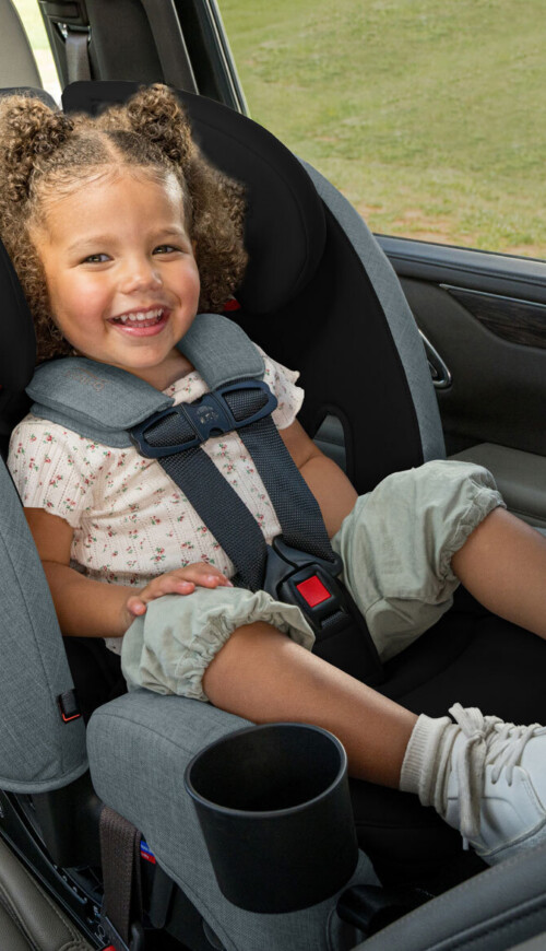 Child smiling in an all-in-one car seat in rear-facing position