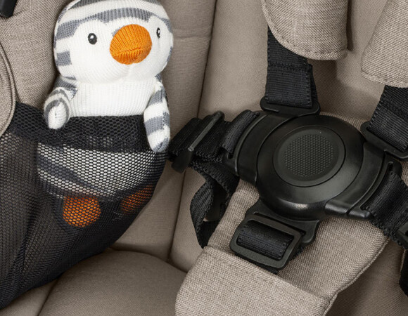 A plush child’s toy inside the mesh seat pocket of a stroller.