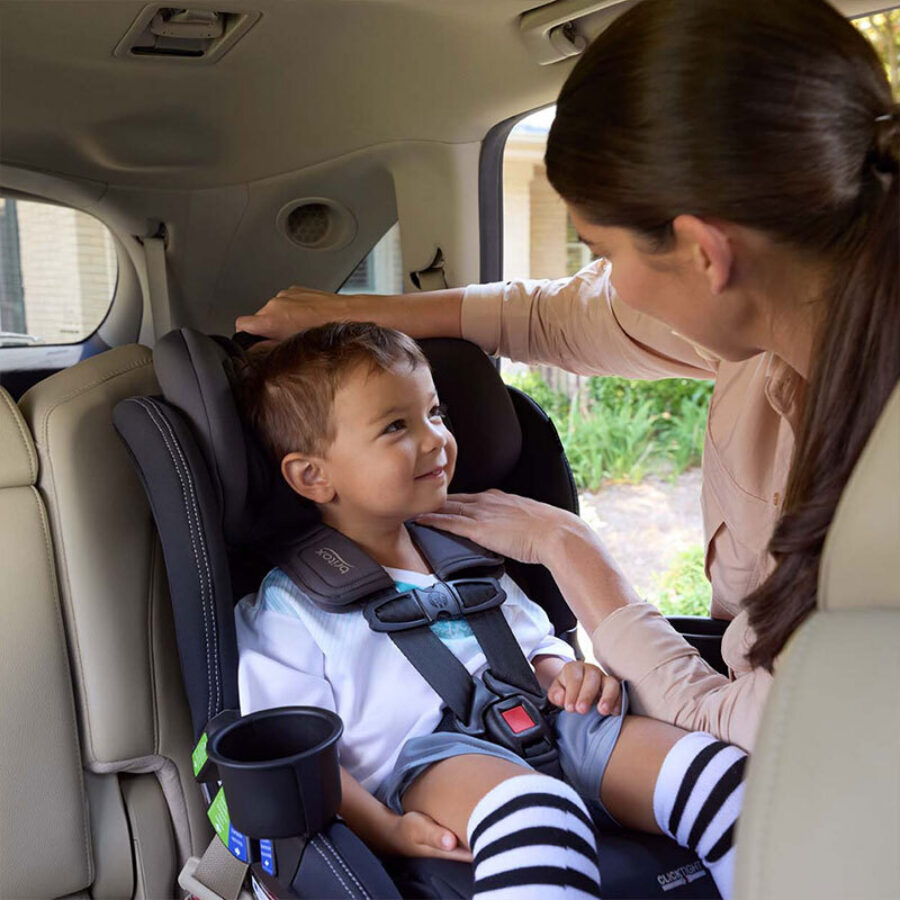 Someone checking the harness height of a forward-facing car seat.