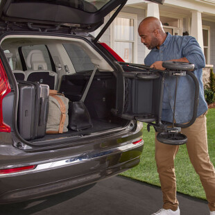 A man putting a stroller into the trunk of a vehicle.