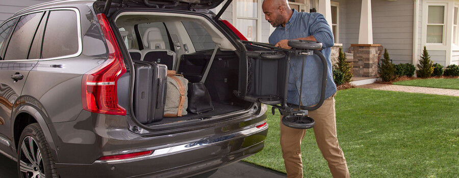 A man putting a stroller into the trunk of a vehicle.