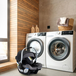 Baby car seat in front of a washer and dryer.