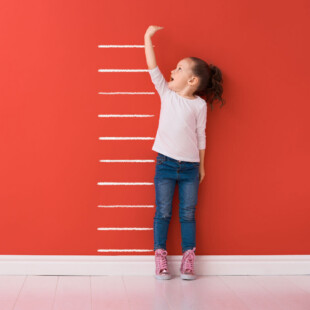 A child standing next to measuring lines on a wall.