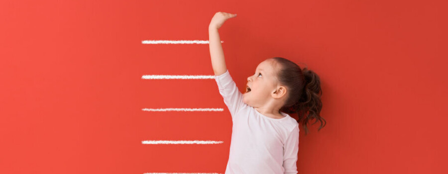 A child standing next to measuring lines on a wall.