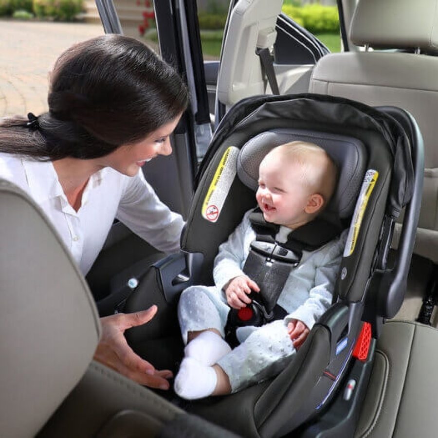 Mother placing child in car seat