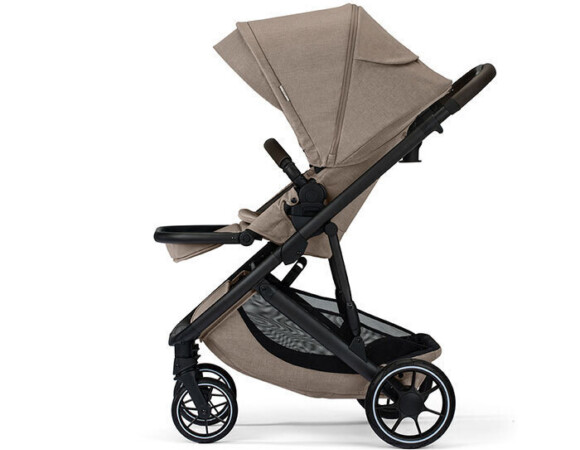 Profile view of a tan stroller with a canopy, bumper bar, footrest, and storage basket.