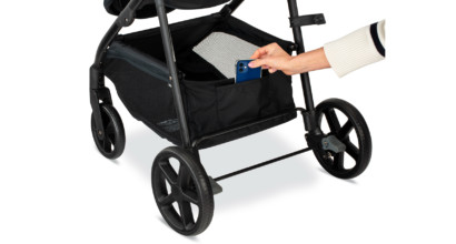Placing a cell phone into a pocket on the back of a baby stroller storage basket.