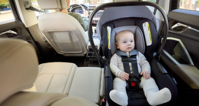 A baby in a rear-facing infant car seat in the back of a vehicle.