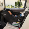 A smiling baby in a rear-facing rotating convertible car seat, which is installed in the back seat of a vehicle.